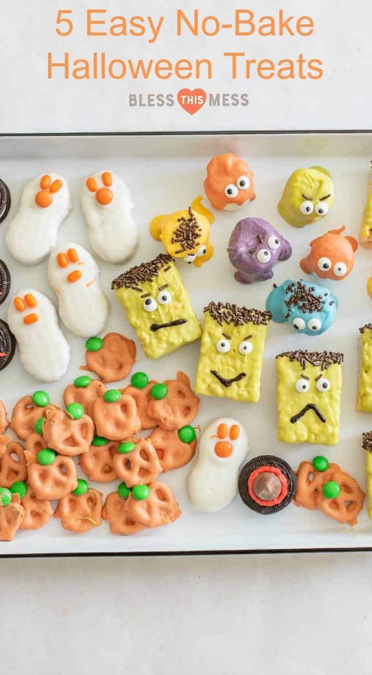 A tray of colorful halloween treats, featuring ghost-shaped snacks, orange pumpkin pretzels, monster rice crispy treats, and Oreo eyeballs—all decorated with candy eyes and festive colors.