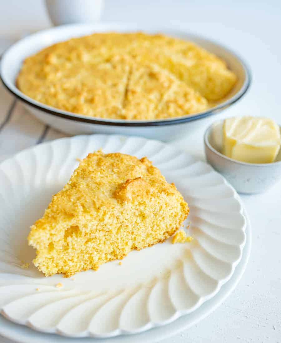 easy sour cream cornbread slice on white plate and butter.