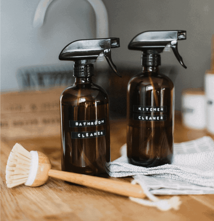 Image of homemade cleaners in dark brown bottles with black handles.