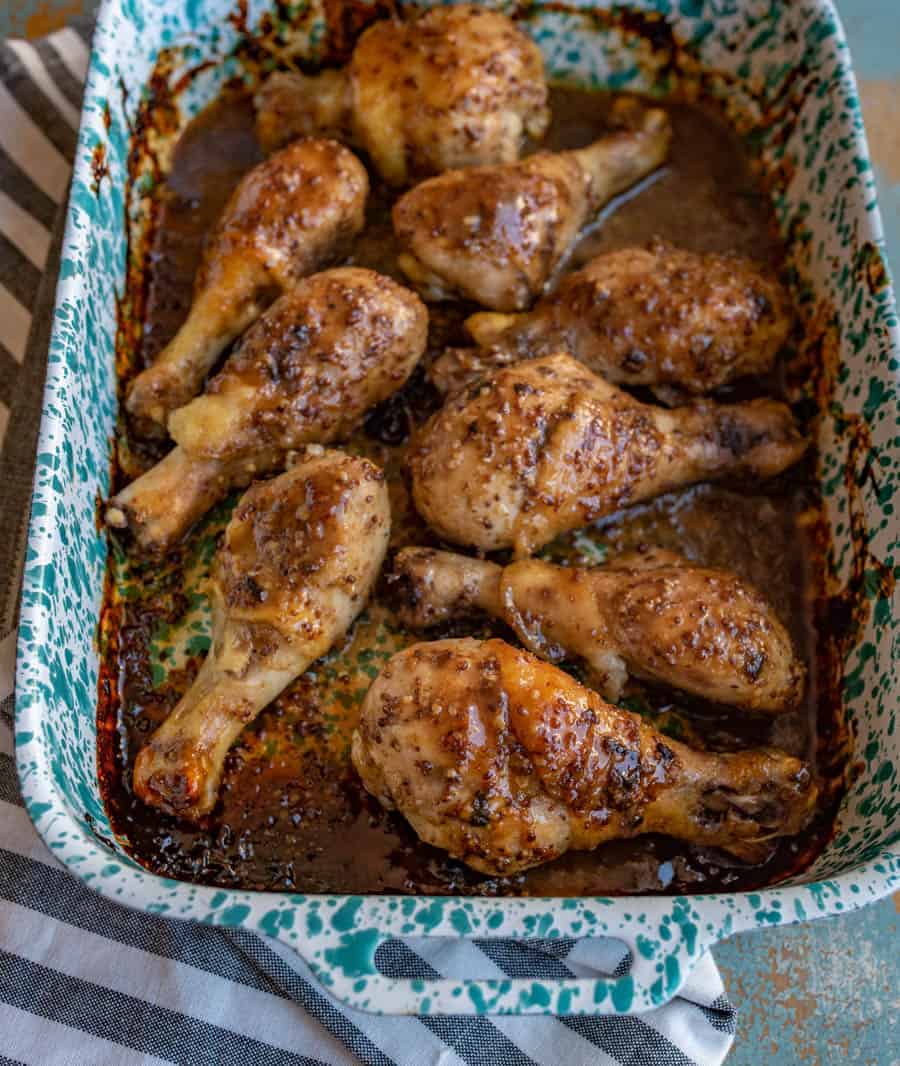 a closeup shot of honey mustard baked chicken legs sitting in a baking dish.