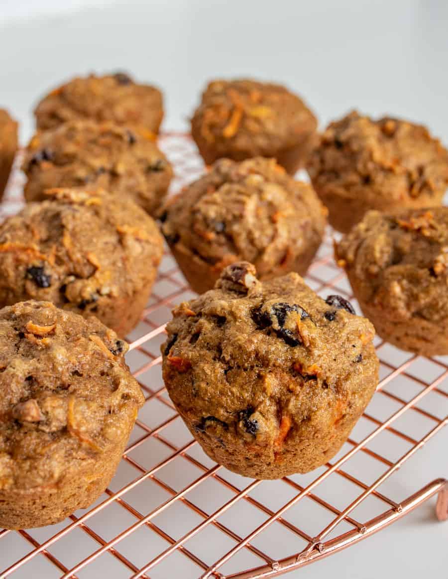 muffins on a metal rack with carrot pieces and raising showing through top.