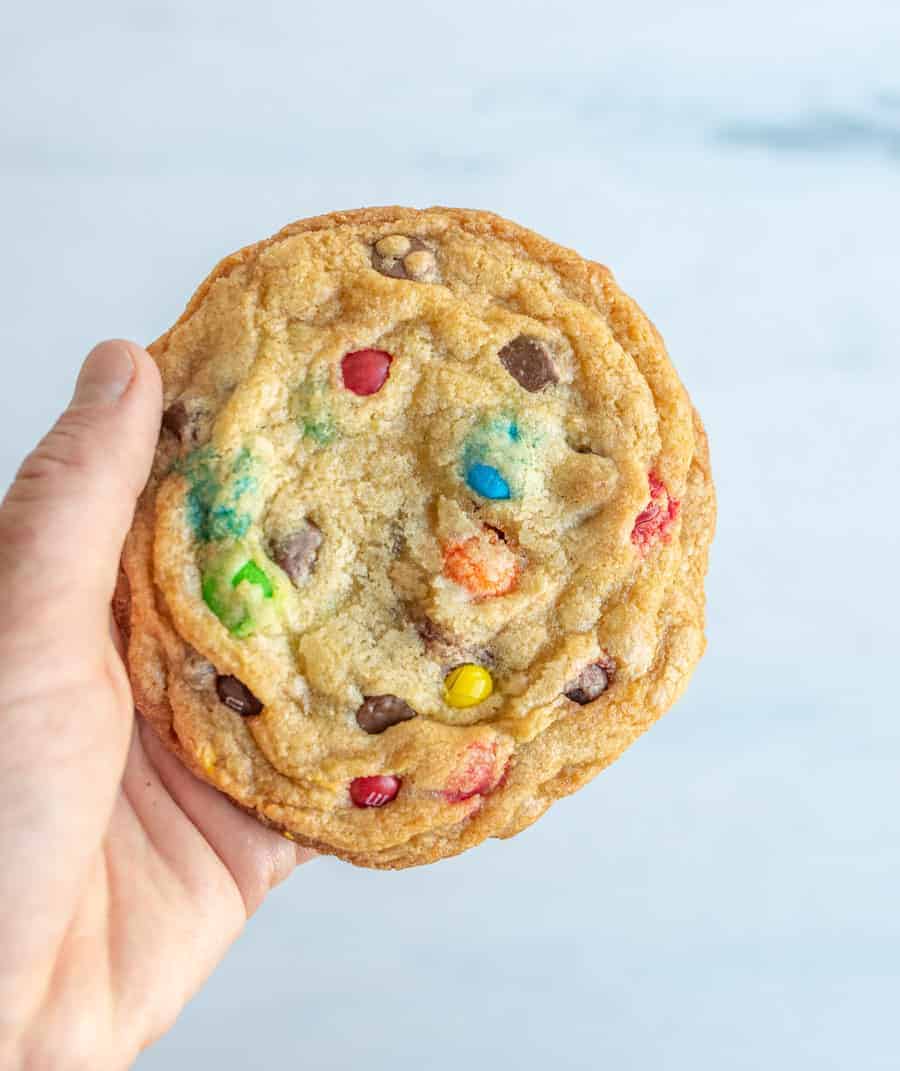 pov hand holding monster chocolate chip m and m cookies.