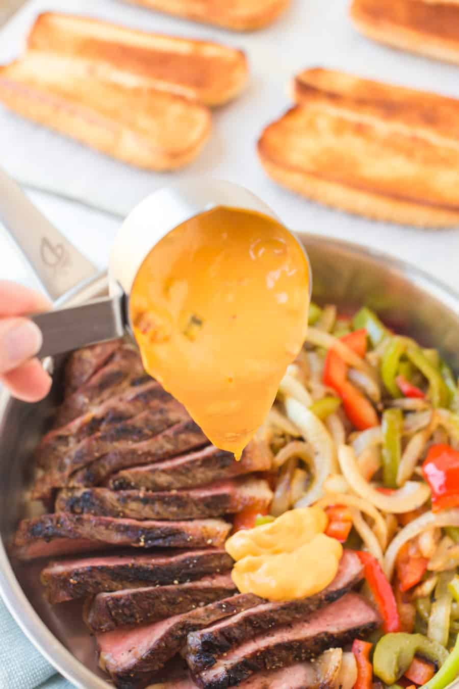 cheese sauce scooped onto steak and veggies.