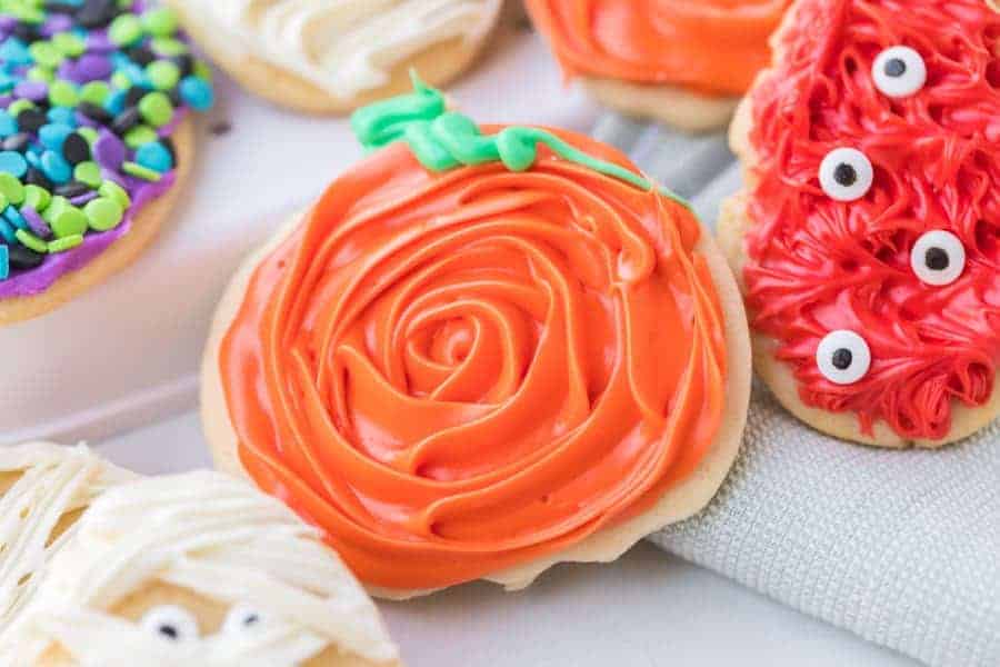 sugar cookies decorated with halloween theme white frosting to look like a mummy with candy eyes and colored sprinkles in purple black green and blue colors red with googly eyes to look like monsters.
