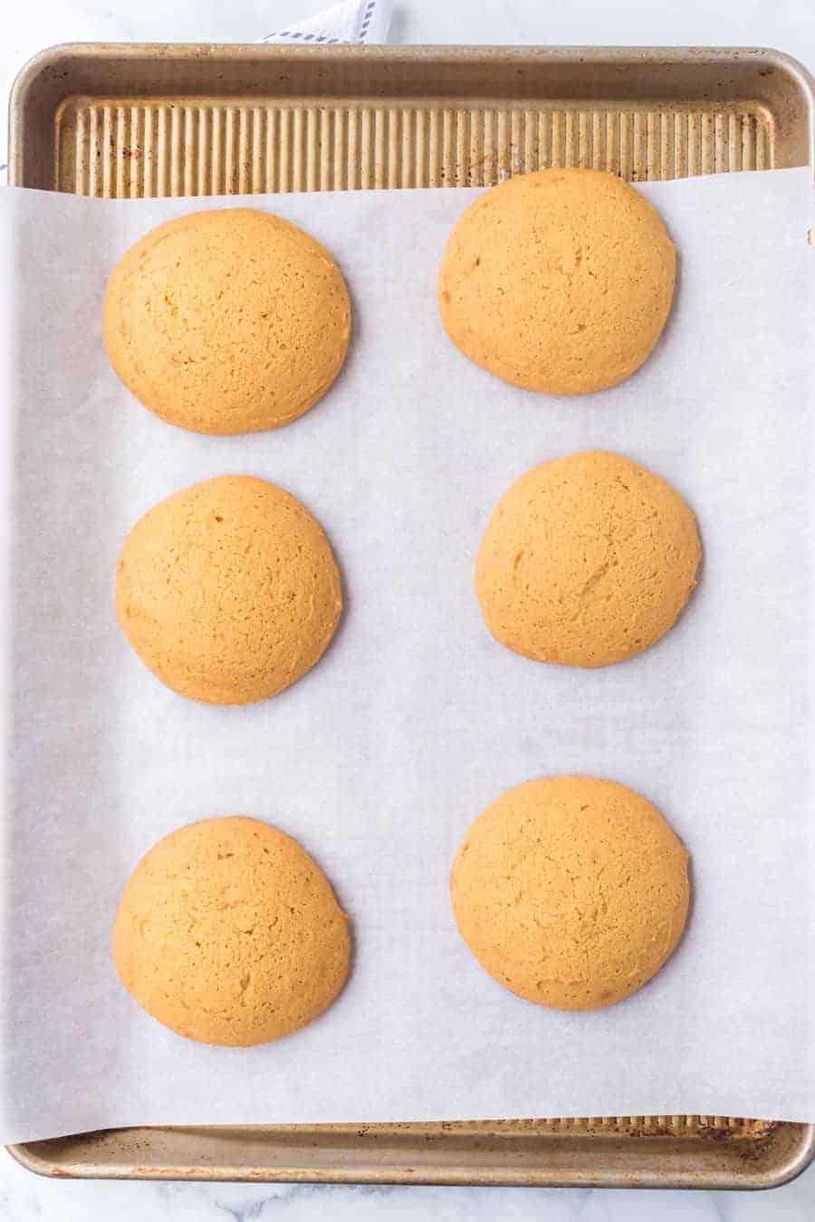 pumpkin whoopee pie tops and bottoms on a baking sheet.