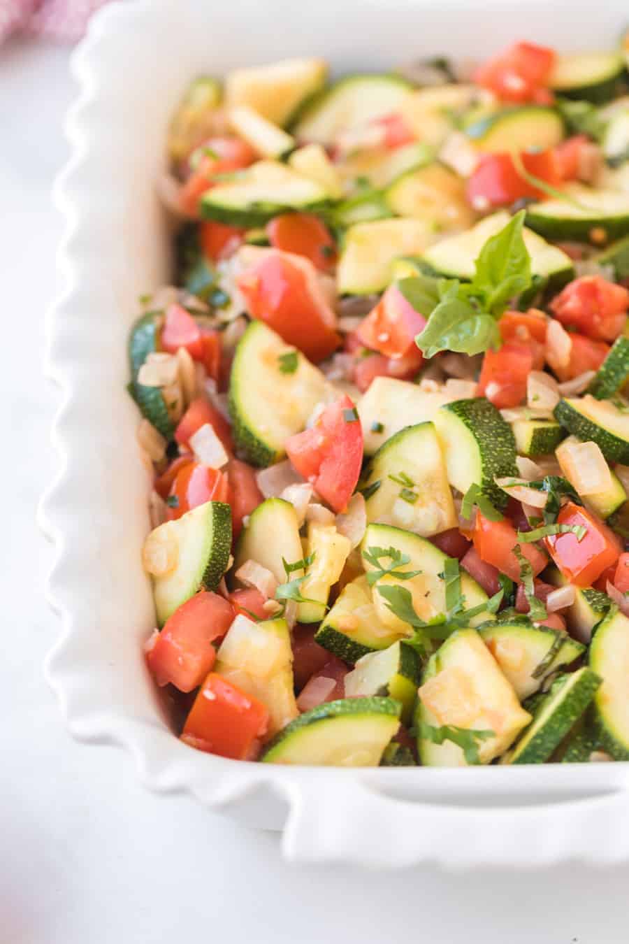 zucchini and tomato in a baking pan for a side dish with zucchini recipe.