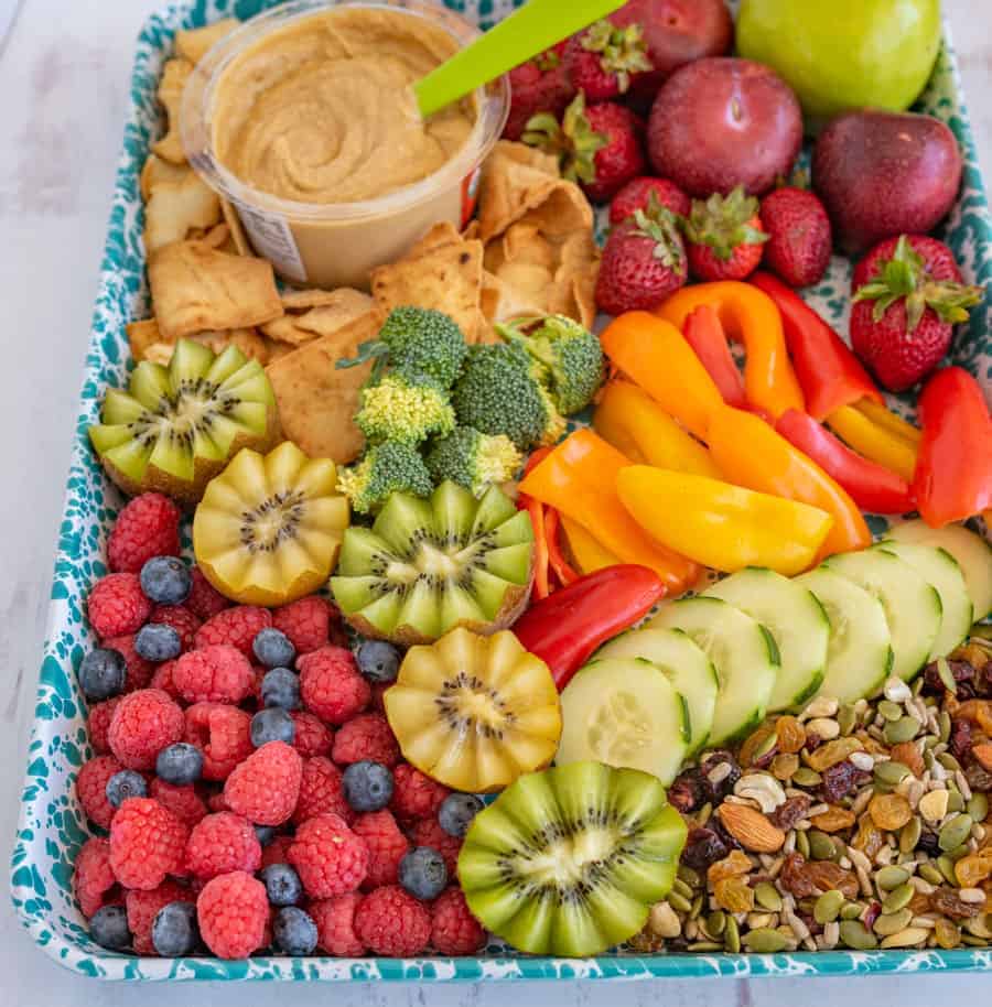 blue-green and white tray piled with assorted fruits, vegetables, and snacks.