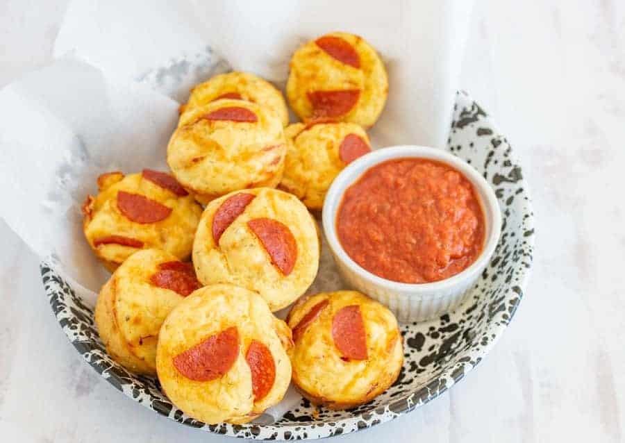 pizza bites in a bowl with marinara sauce on the side.