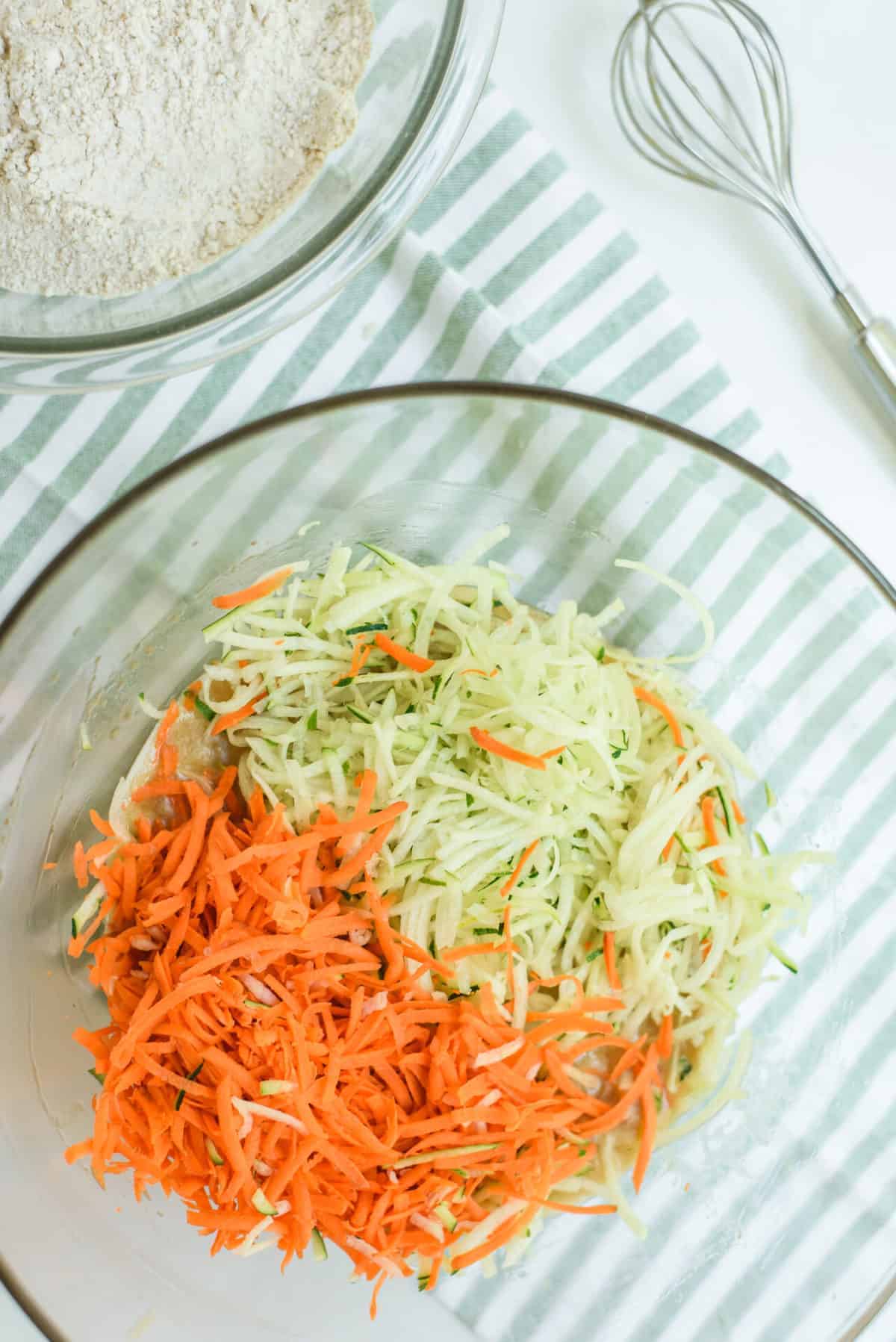 shredded carrots and zucchini in a glass mixing bowl.
