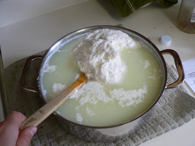 Homemade Cottage Cheese curdling in a pan on a gray towel.
