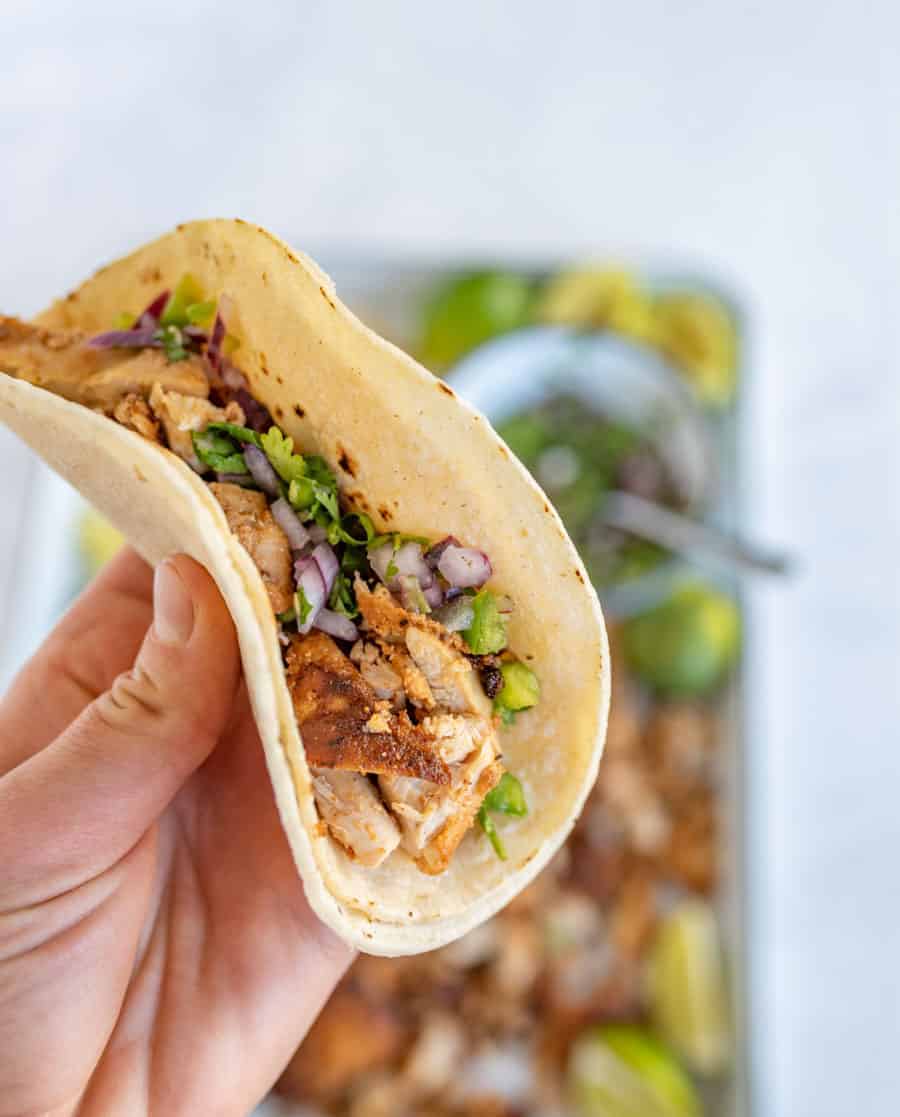 woman holding chicken taco made with two tortillas.