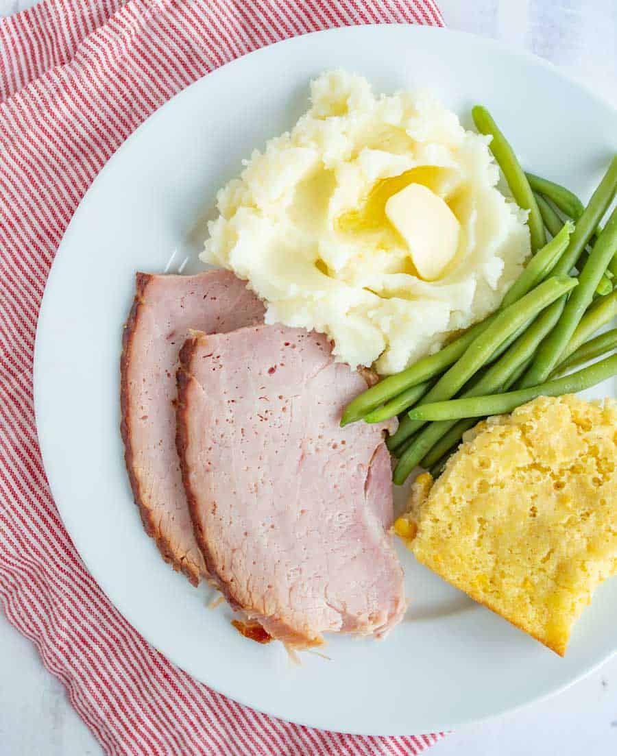 corn casserole green beans mashed potatoes on a white plate.