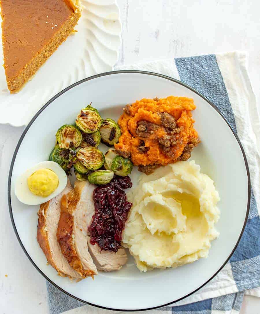 Thanksgiving dinner plate with mashed potatoes deviled egg brussels sprouts sweet potato casserole mashed potatoes turkey and cranberry sauce.
