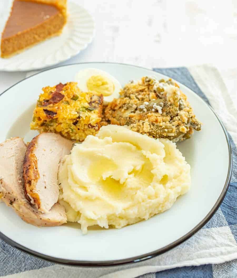 casserole made with green beans. mashed potatoes turkey on round white plate.