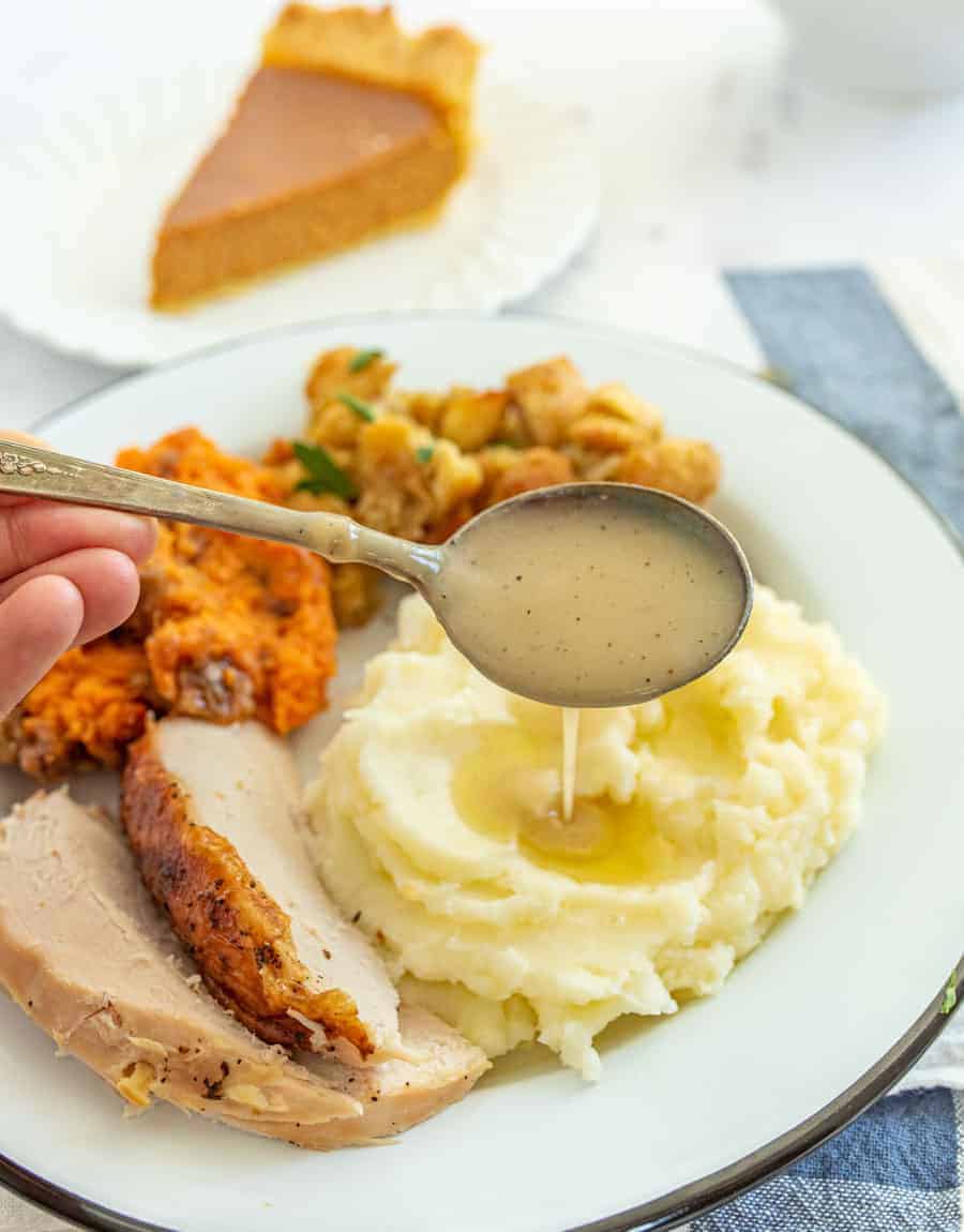 spoon full of gravy dripping over mashed potatoes.