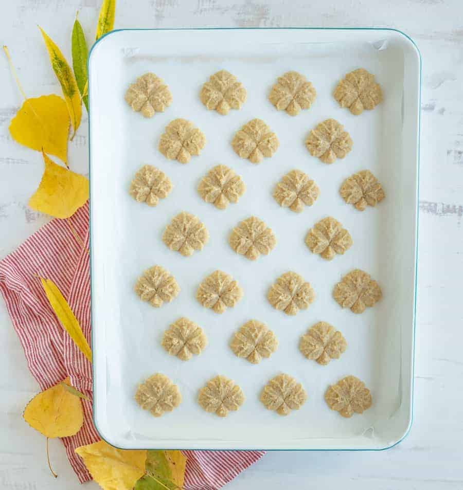 pumpkin spice spritz cookies on a parchment baking dish.