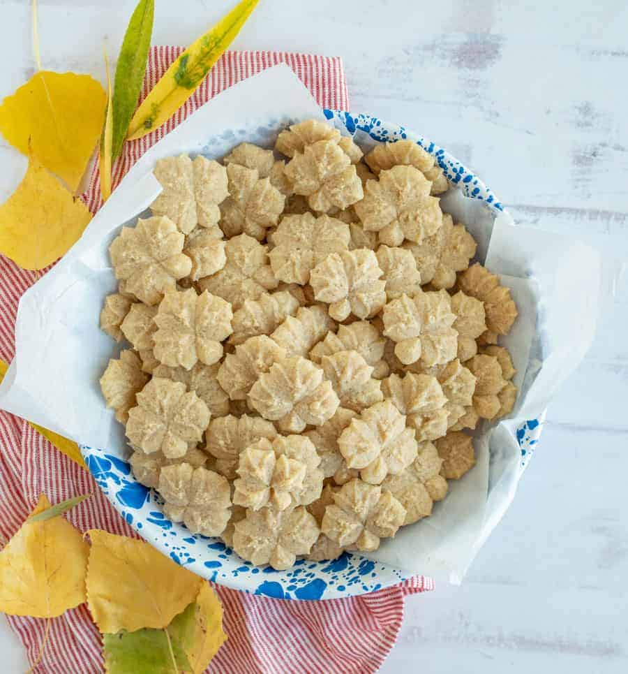 A blue and white bowl filled with small flower cookies.