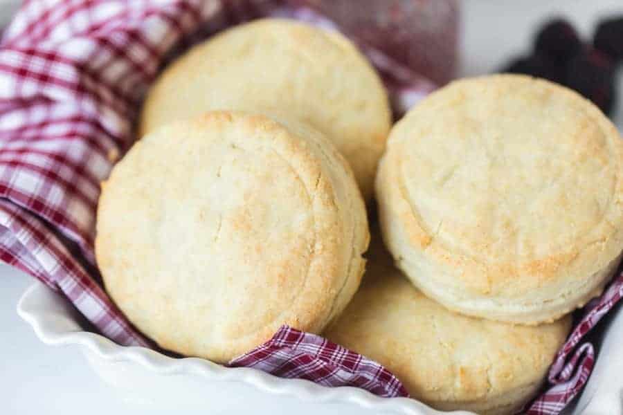 biscuits wrapped in red and white checked towel in white dish.