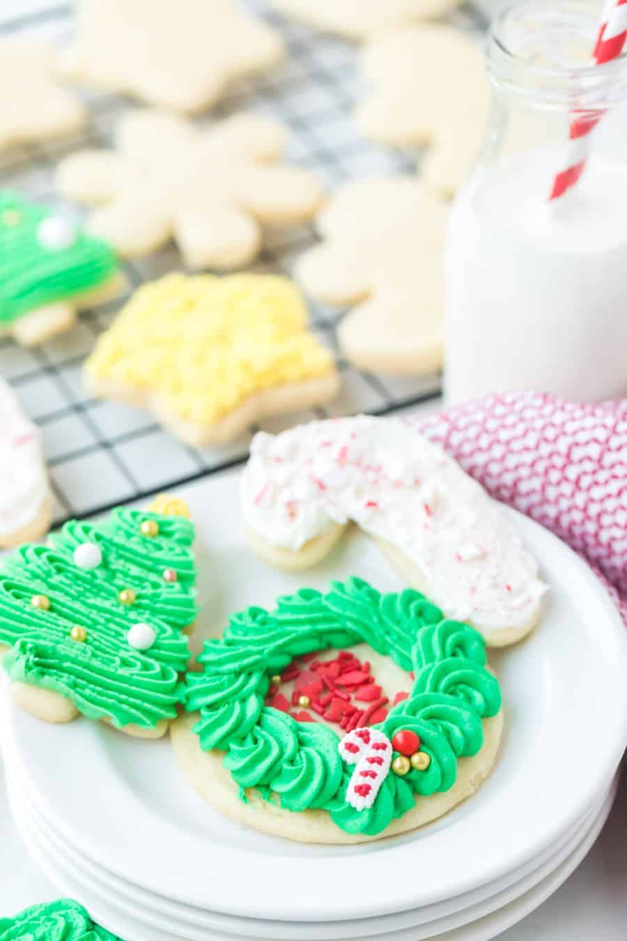 holiday decorated sugar cookies iced next to a glass jug of milk.