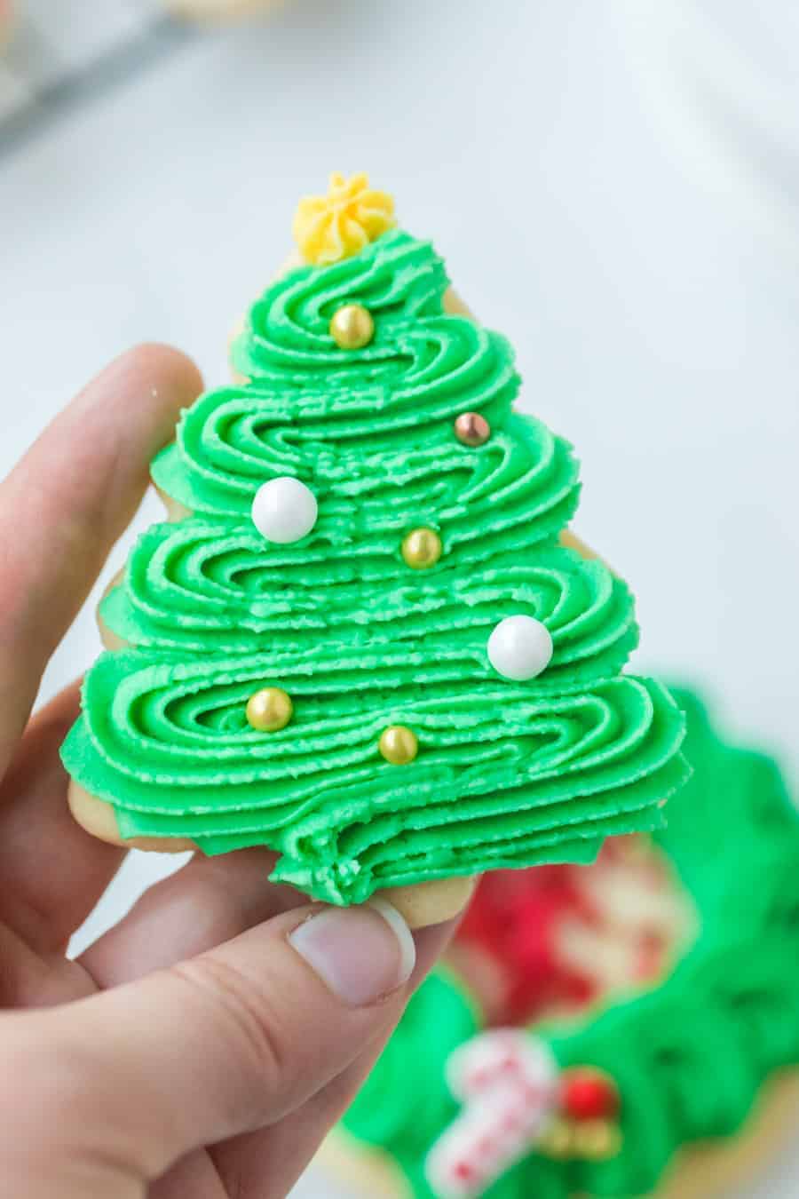 holiday decorated sugar cookies iced with green icing in the shape of a tree.
