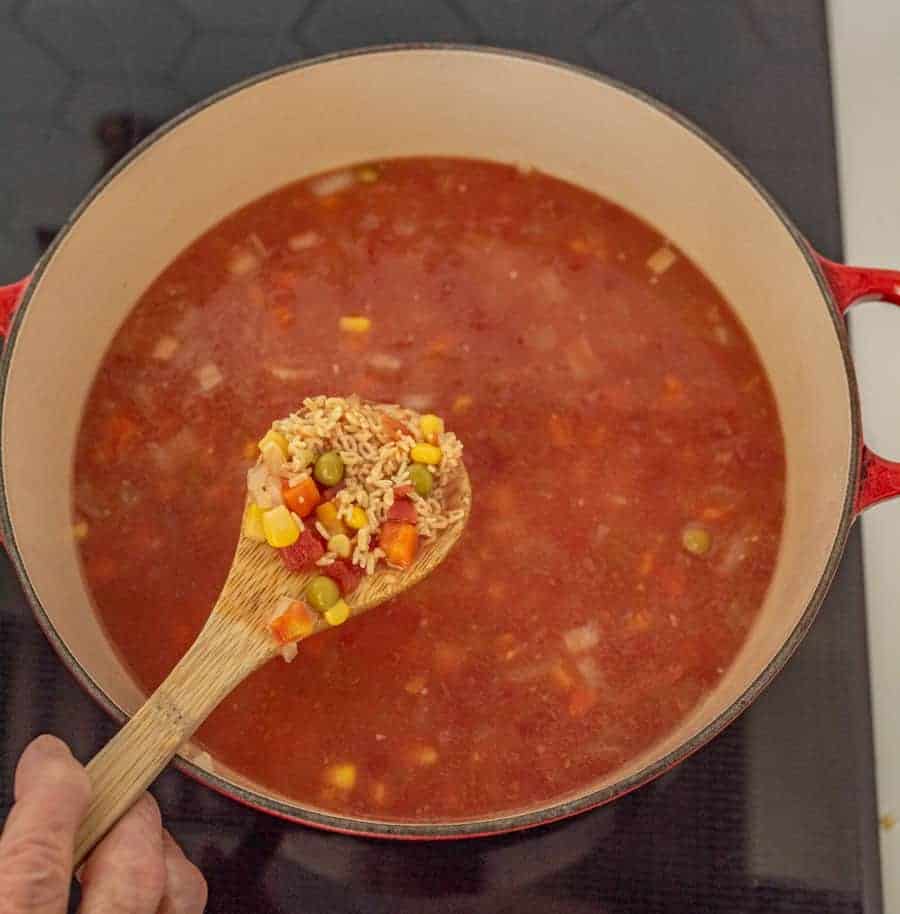 top view of alphabet soup in red cast iron pot spooning out.
