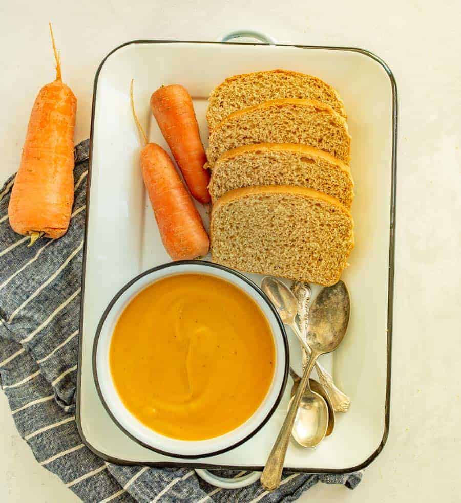 tray with bowl of carrot soup and homemade bread.