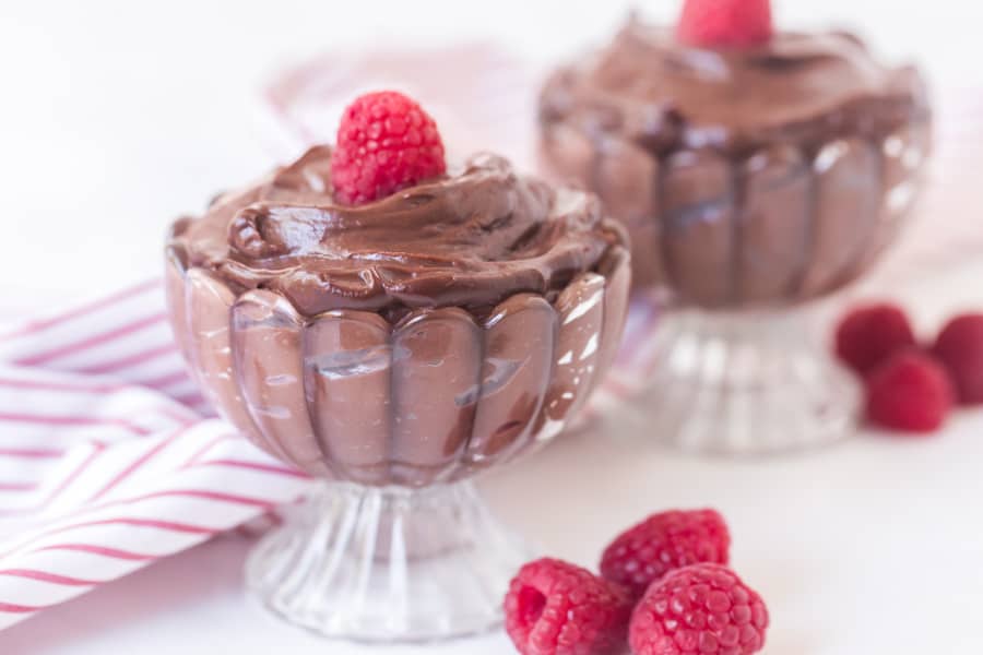 chocolate pudding in a pretty dish with raspberry on top.