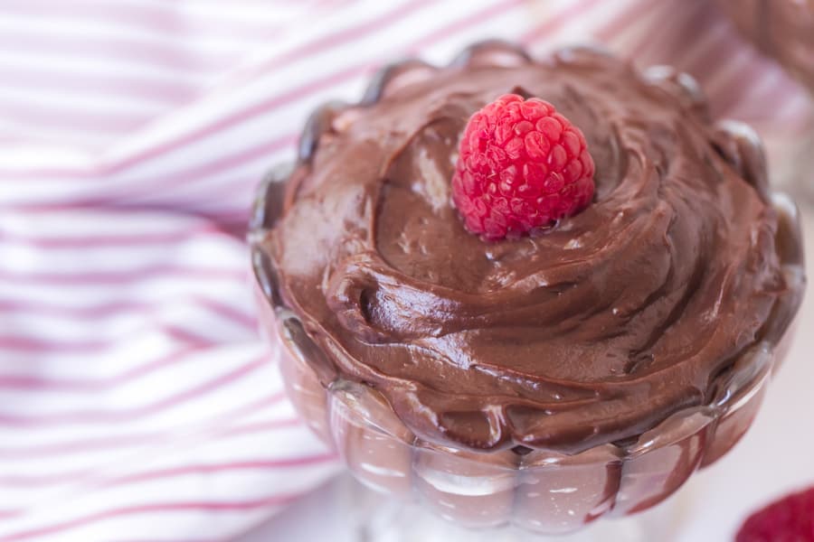 chocolate pudding in a pretty dish with raspberry on top.