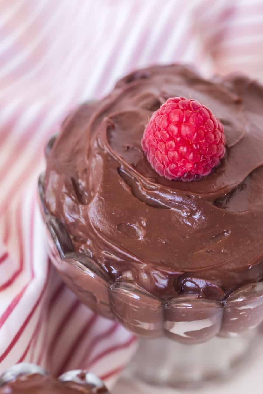 chocolate pudding in a pretty dish with raspberry on top.