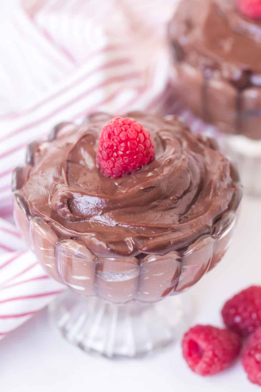 chocolate pudding in a pretty dish with raspberry on top.