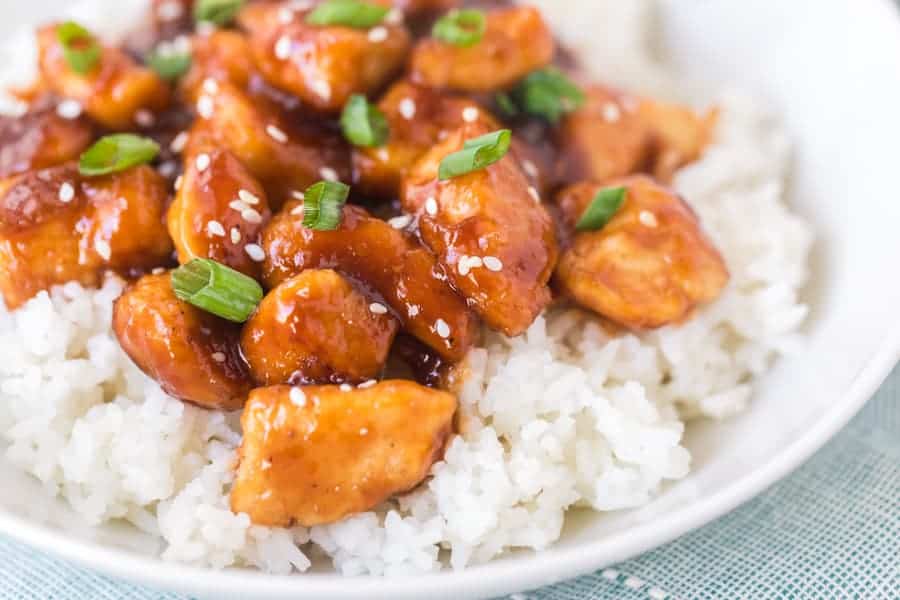 General Tso's Chicken with White Rice in white bowl on blue towel.