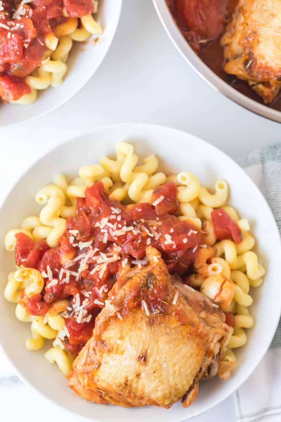 tomato and garlic cavatappi pasta with chicken thigh in white bowl.