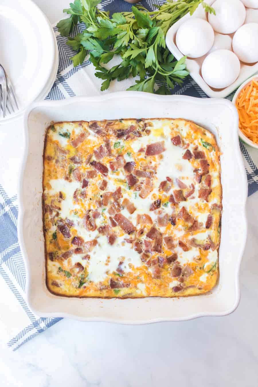 Top view of a bacon, egg, and cheese bake in a white ceramic dish.