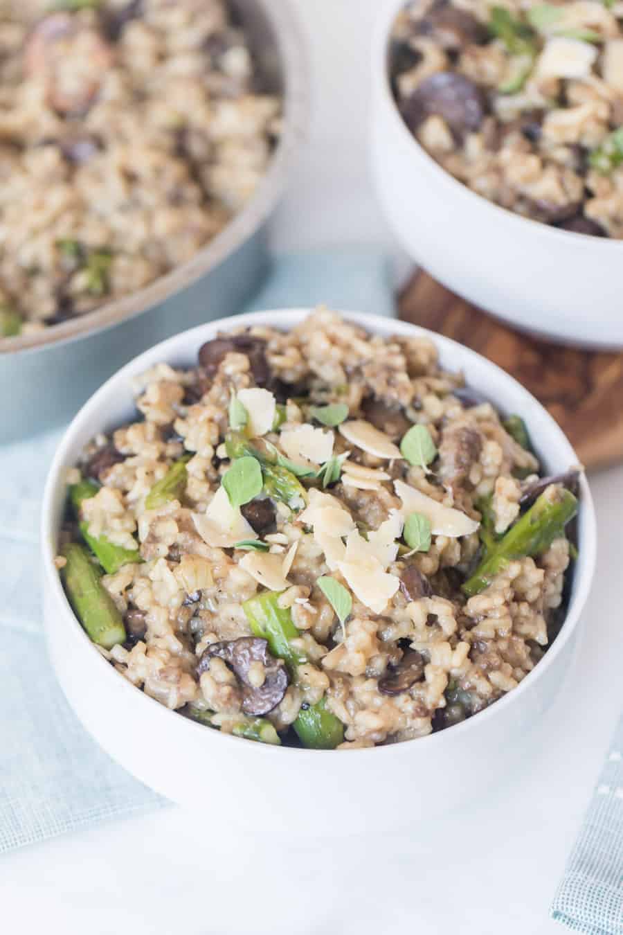 Risotto with sausage and mushroom in white bowls.