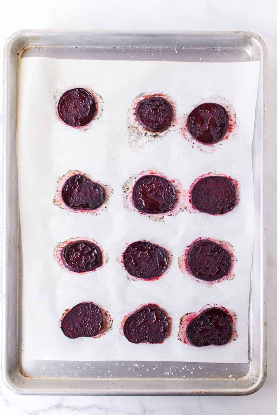 top view of a baking sheet with slices of round thin roasted beet pieces