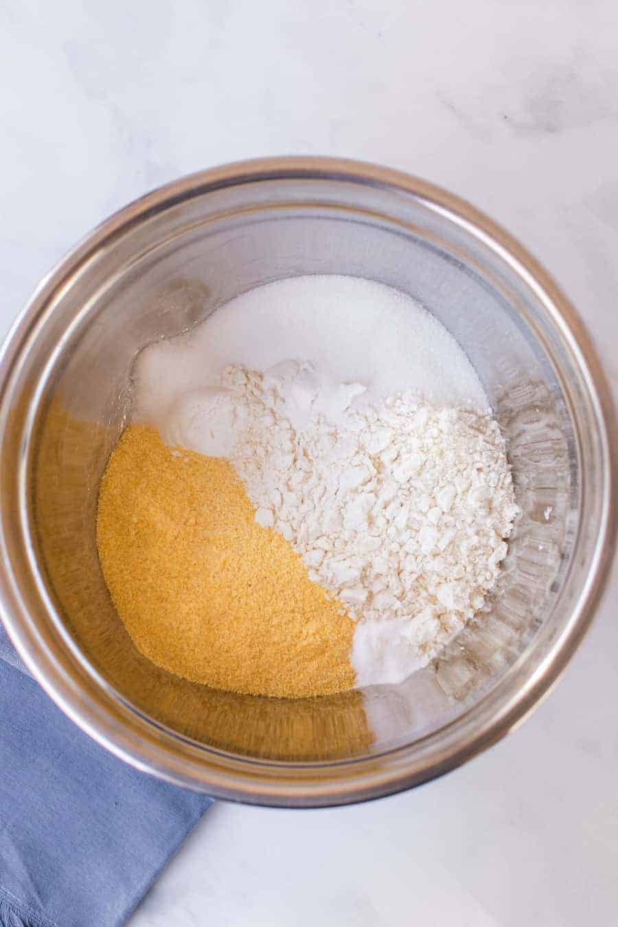 top view of ingredients for cornbread batter in a metal mixing bowl.