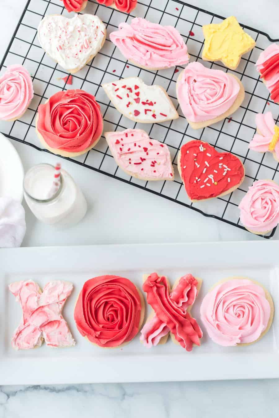 stack of valentines day sugar cookies with piped pink and red or lips or even X&O's made of frosting.