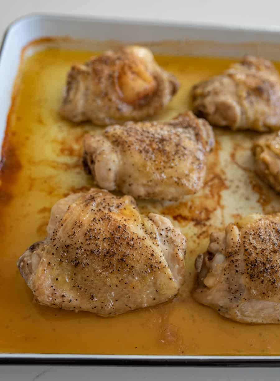 side view of the pan full o seasoned and cooked chicken thighs.