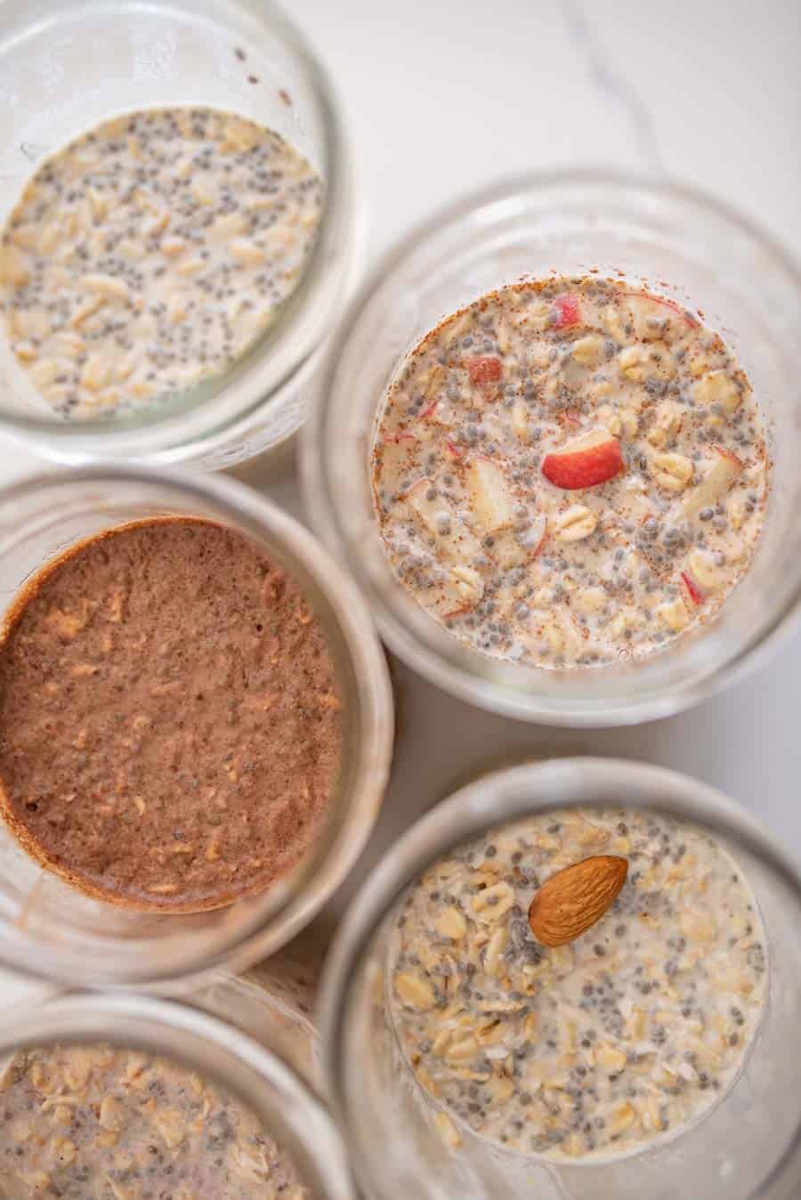 close up of 5 kinds of overnight oats in glass jars from the top.
