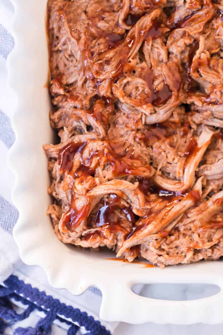 close up of the corner of top view of the baking dish of BBQ pulled pork.