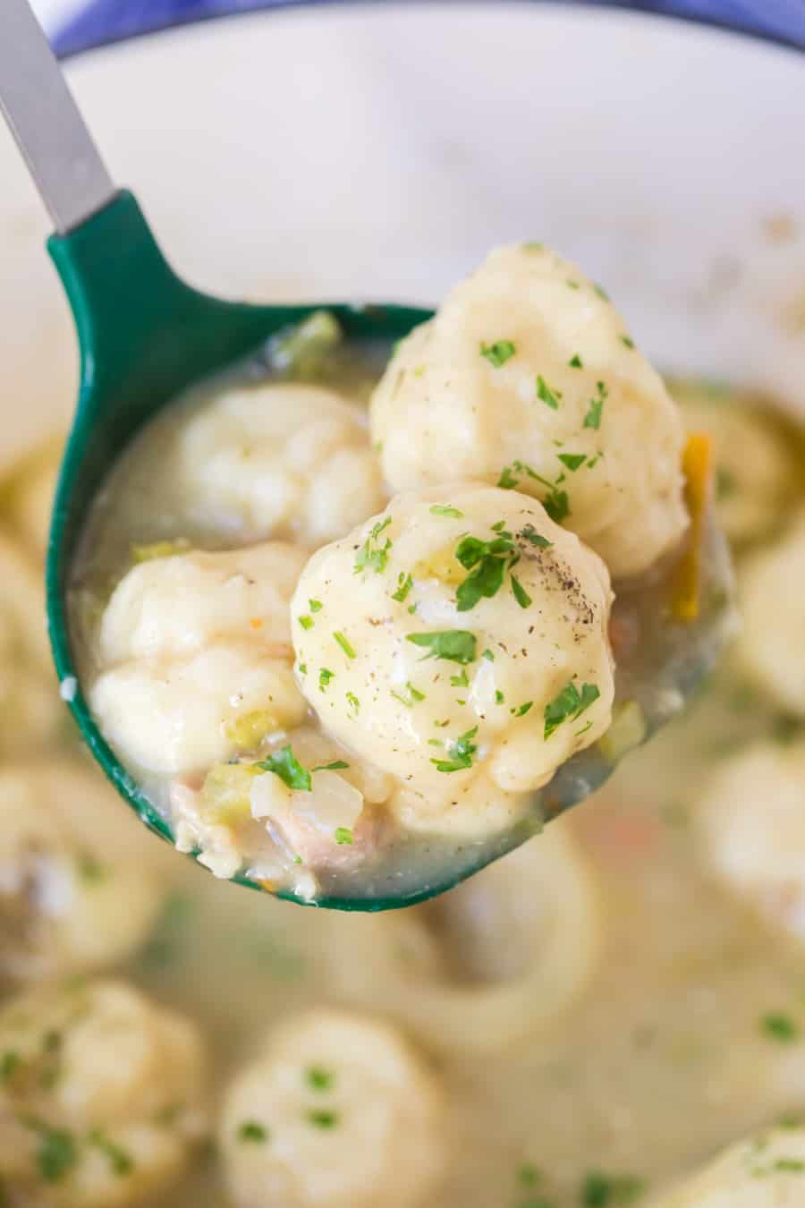 closeup image of dumplings and soup in ladle with parsley garnish.