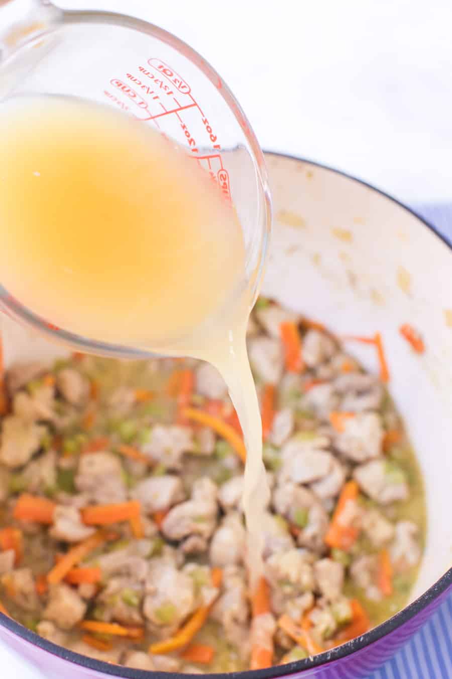 broth going into chicken and dumpling soup dutch oven