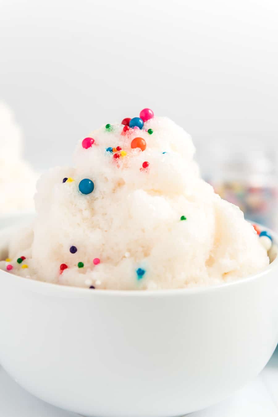 Close up of a white bowl with snow cream and sprinkles.