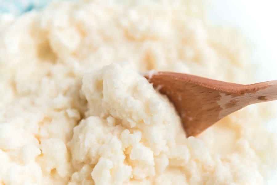 A wooden spoon scooping vanilla snow ice cream.
