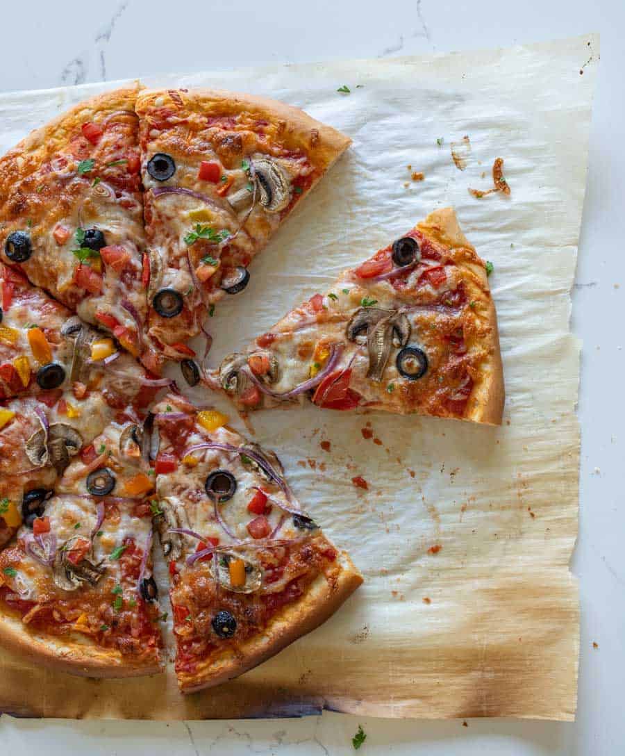 homemade veggie pizza with slices missing on parchment