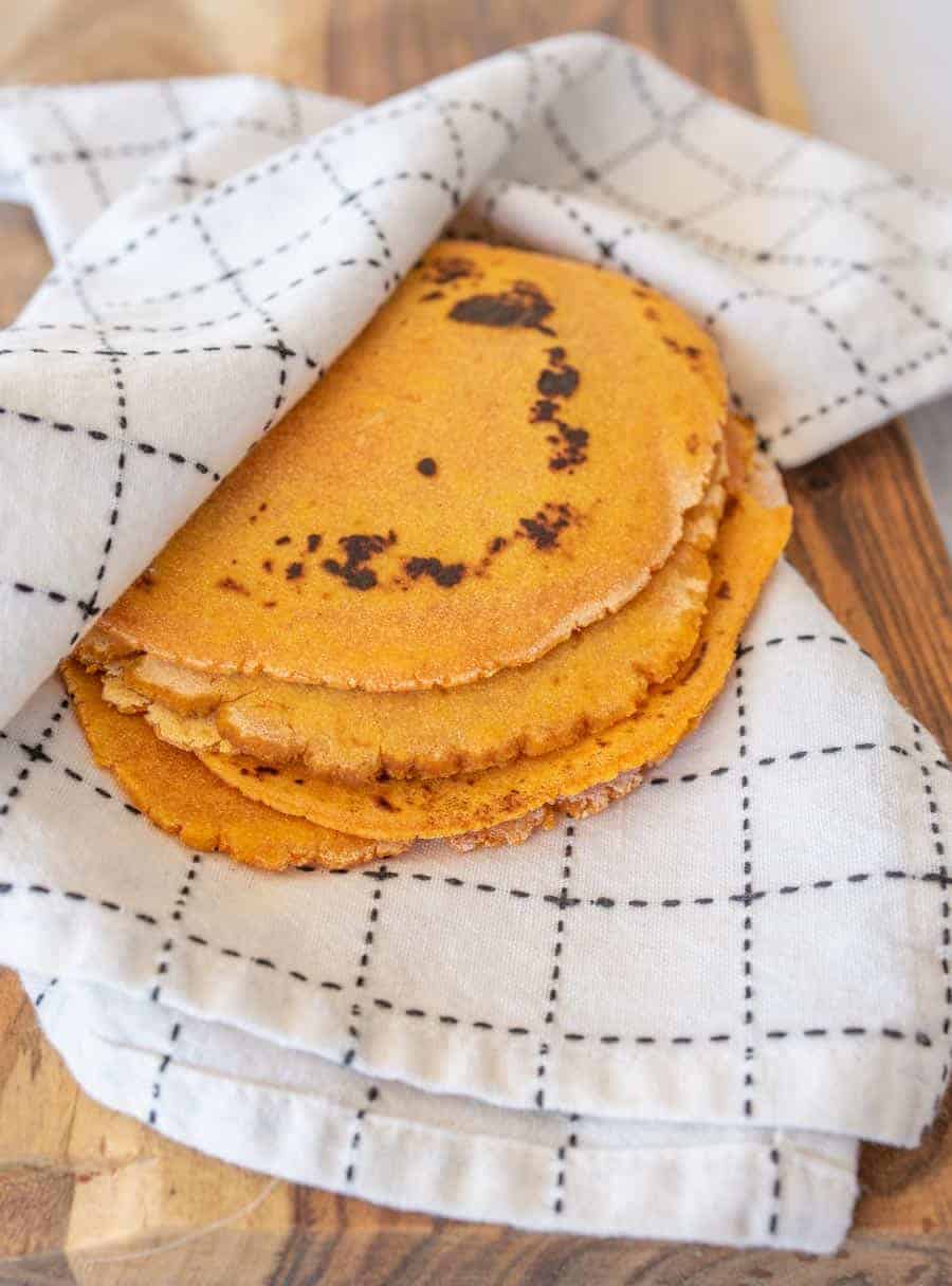 Stack of four tortillas in a white and black kitchen towel.