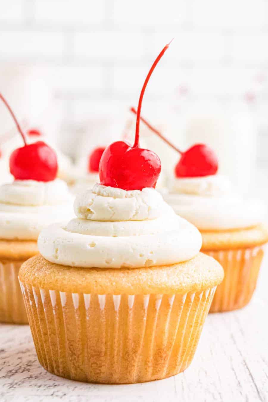 Cluster of close up cherry chip cupcakes with maraschino cherries on top of each one.