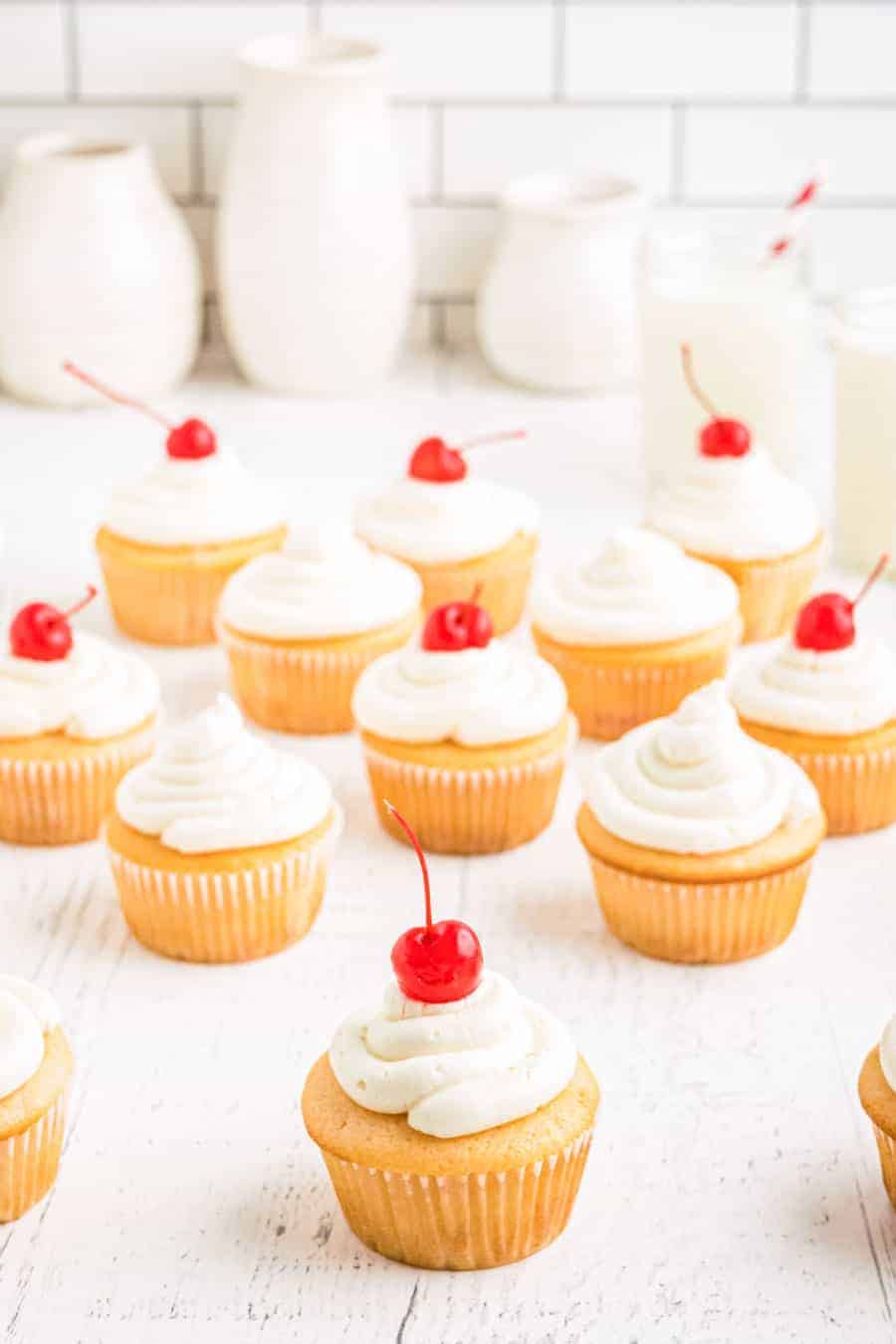 Cluster of cupcakes on a white countertop with white subway tile backsplash in the background.