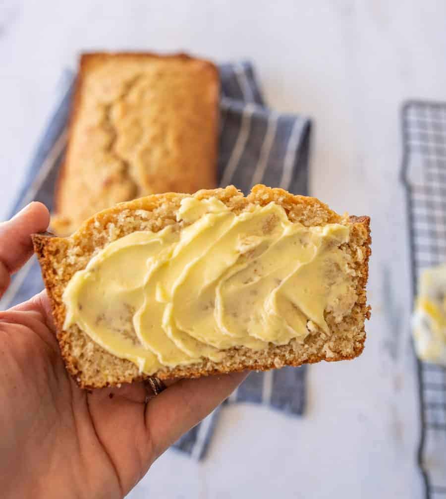 A slice of banana bread with lots of yellow butter on top.