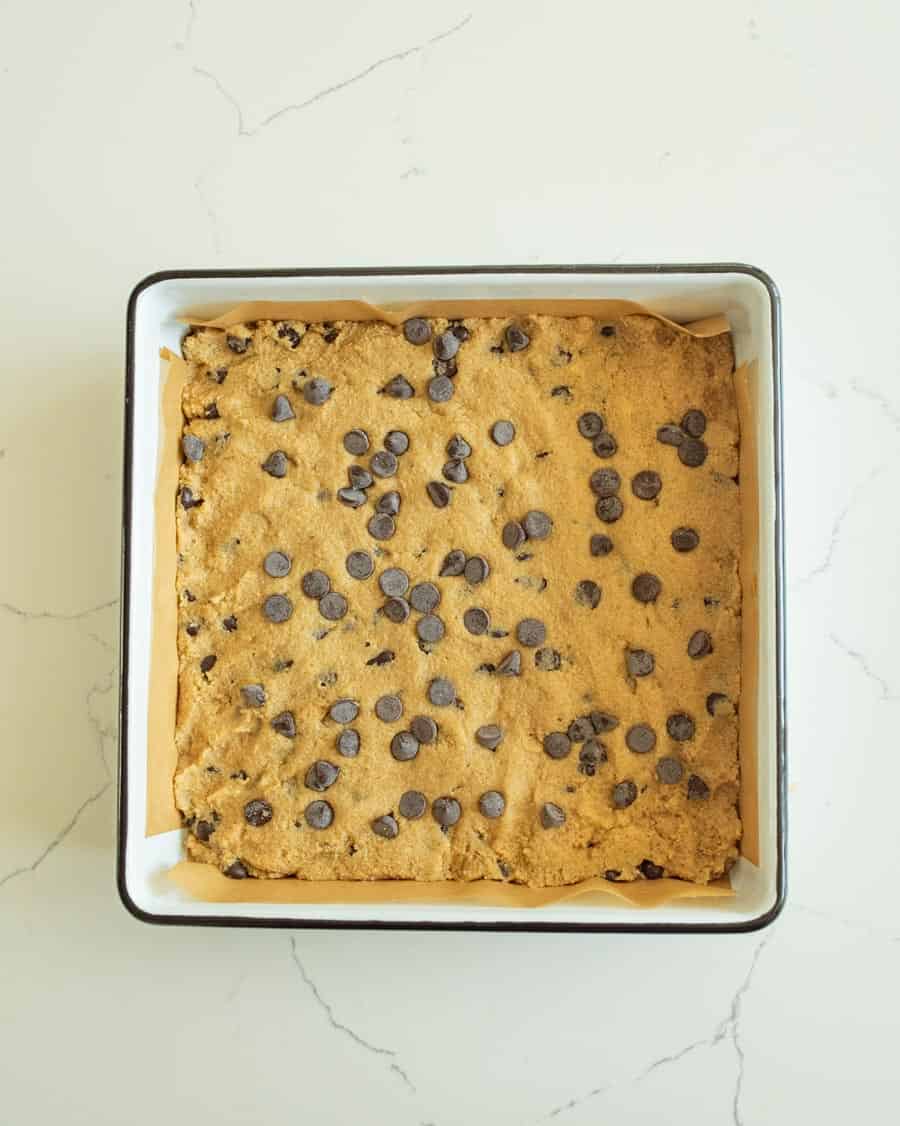 almond flour cookie dough pressed in pan with chocolate chips on top.